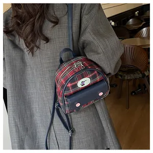 Détail d'un mini sac à dos à carreaux avec écusson d'ours et boutons roses