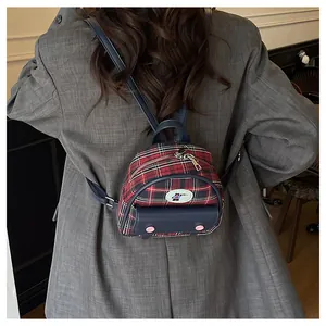 Close-up of a mini red plaid backpack with navy leather straps on a grey blazer