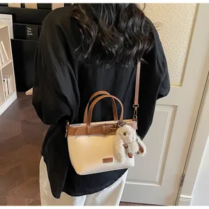 Détail du sac seau beige et marron avec breloque lapin en peluche et bandoulière réglable