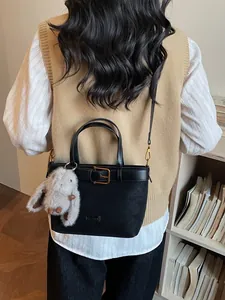 Sac seau noir mat avec breloque lapin et boucle de ceinture porté par un modèle