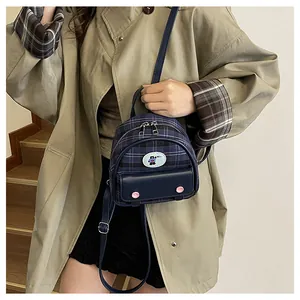 Close-up of a mini navy plaid backpack with leather pocket and cute bear patch detail