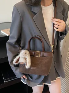 Sac seau vintage marron mat avec breloque lapin en peluche porté par un mannequin