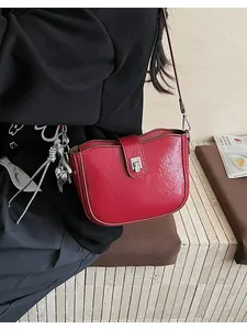 Close-up of red textured leather handbag with silver heart charm and metal buckle