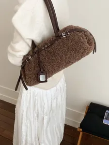 Brown faux fur cylindrical tote bag with leather straps worn by a model in a minimalist setting