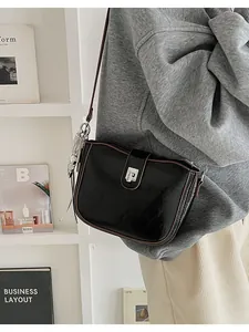 Detail of a vintage black saddle bag with brown trim and a silver skull charm accessory