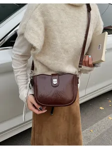 Close-up of a vintage brown leather saddle bag with silver metal swivel lock detail