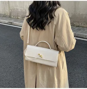 Outdoor-Straßenszene mit der strukturierten cremefarbenen Ledertasche und Goldverschluss