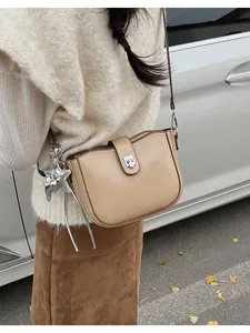 Detail of beige leather crossbody bag with silver star charm and elegant fringe tassel