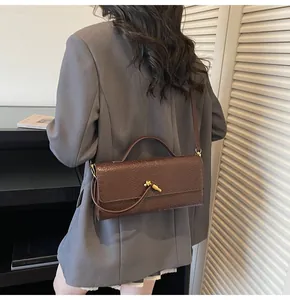 Detail der dunkelbraunen Baguette-Tasche mit Tiertextur und goldener Knotenschnalle