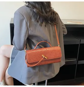 Detail der rotbraunen Schlangenhaut-Tasche mit goldenem Knotendetail und eleganter Textur