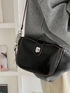 Minimalist black leather crossbody saddle bag with brown trim and silver buckle shown on model