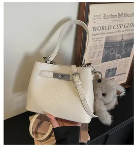 Detail of creamy bucket bag in pebble leather with silver twist lock and plush bunny charm