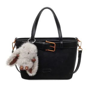 Dettaglio borsa tote in pelle scamosciata nera con manici in pelle e ciondolo a coniglietto