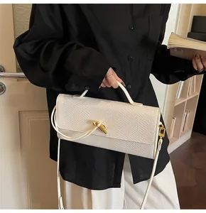 Detailansicht der weißen Handtasche mit Schlangenmuster und goldenem Drehverschluss-Detail