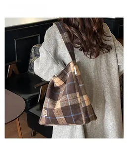 Detail view of large plaid tote bag in brown wool fabric on model wearing grey coat