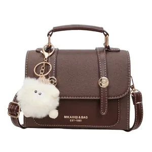 Retro brown crossbody bag with gold hardware and a cute white plush pendant