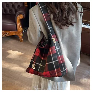 Detailed close-up of a red and black plaid tote bag with a bear patch and soft texture