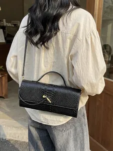 Schicke schwarze Baguette-Tasche in Schlangenoptik mit goldenem Metall-Drehverschluss