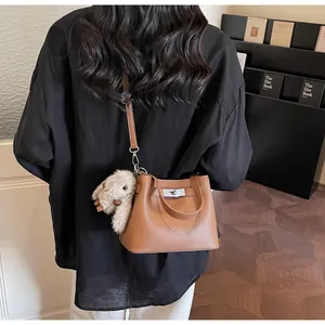 Brown litchi leather bucket bag shown from behind with a cute plush rabbit charm
