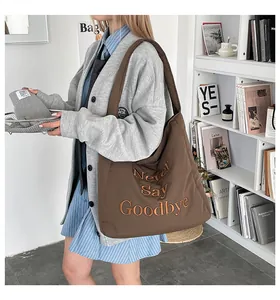 Détail du sac cabas en toile marron avec broderie texte Never Say Goodbye dessus