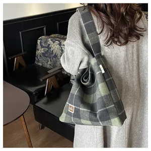 Detail of green plaid wool tote bag showing textured fabric and bear logo patch