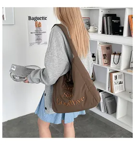 Détail d'un sac cabas marron avec broderie 'Never Say Goodbye' et texture souple