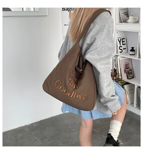 Détail de la broderie Never Say Goodbye sur un cabas en toile marron avec bandoulière