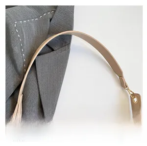 Detail view of reinforced wide strap and gold hardware on beige tote bag