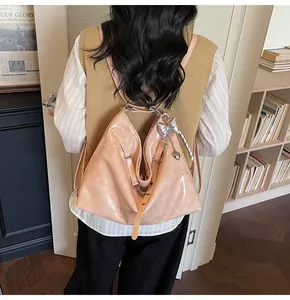 Detail view of beige patent leather tote bag featuring silver chain and heart charm