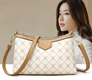Close-up of white crossbody bag with golden geometric pattern and leather details