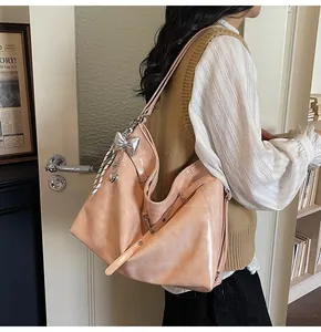 Close-up of peach pink hobo bag with shiny leather texture and silver bow charm