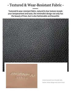 Detail van zwart kunstleer met lychee-patroon en metalen logo op een modieuze tas