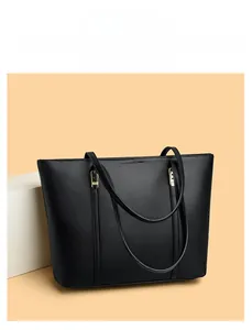 Détail du sac cabas en cuir noir montrant le grain de litchi et les boucles dorées