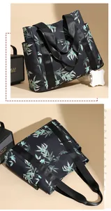 Detail of black tote bag featuring green bamboo leaf prints and wide woven handles
