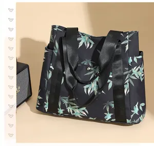 Detail of printed tote bag with green leaf pattern and wide nylon shoulder straps