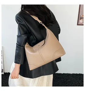 Detailed view of beige hobo tote bag with curved stitching and wide leather shoulder strap
