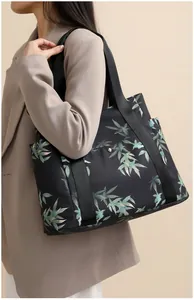 Detailed shot of large capacity black tote bag with green leaf print and silver buckle