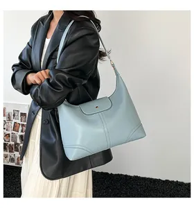 Detail of light blue leather tote bag with semi-circular flap and wide shoulder strap