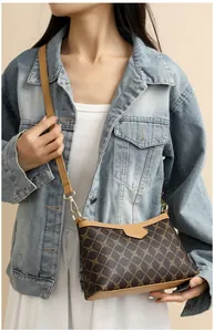 Woman in denim jacket showing the brown leather crossbody bag with pattern