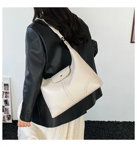 Detail view of cream-colored tote bag with curved stitching and metal buckle on model