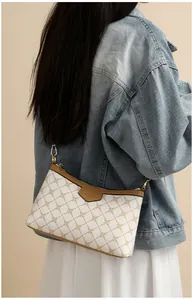 Detail of cream and brown crossbody bag with gold chain print on denim jacket
