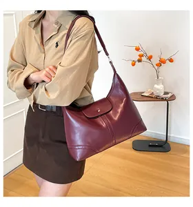 Detail view of large burgundy leather hobo bag with metal buckle and long shoulder strap