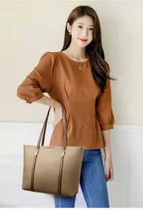 Vue détaillée du sac cabas en cuir marron avec des boucles métalliques dorées élégantes
