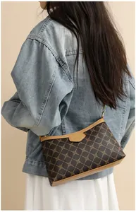 Detail of crossbody bag featuring golden diamond patterns and brown leather strap
