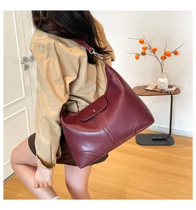 Woman carrying large burgundy tote bag with smooth leather and elegant stitching detail