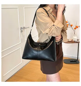Close-up of black leather Hobo bag with gold buckle on model in an indoor setting
