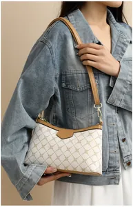 Modern beige shoulder bag with geometric chain pattern and brown leather trim on a model