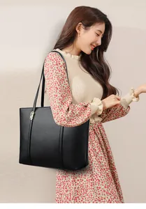 Détail du sac cabas en cuir noir à texture litchi avec des accents dorés élégants