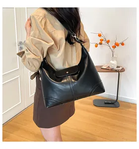 Close-up of black leather hobo tote featuring decorative stitching and gold hardware