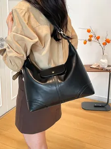 Minimalist black large capacity tote bag shown on model in cozy interior setting